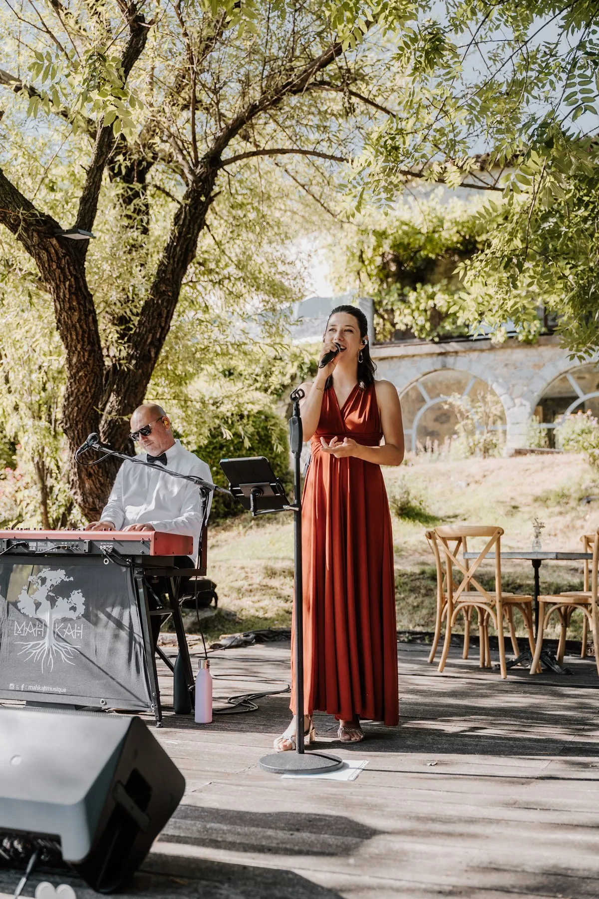 Le duo Mahkah en live lors d'un mariage : Mathilde au chant en robe rouge et Stéphane au piano, en extérieur